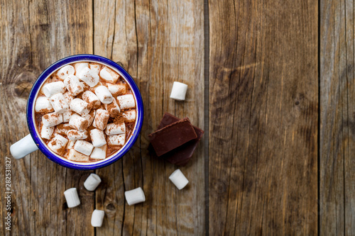 hot chocolate in an iron mug with marshmallow on old wooden background. Copy space, top view