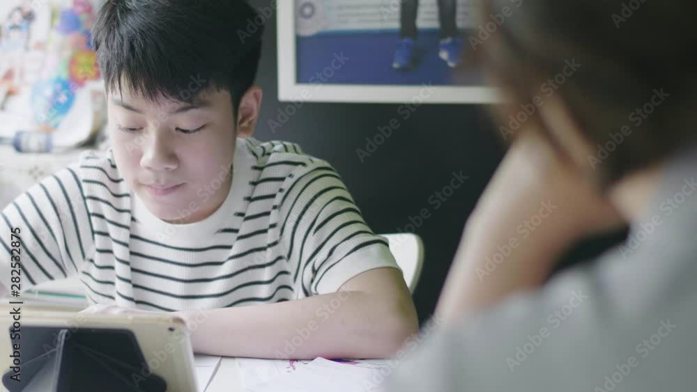 Asian boy doing your homework with tablet computer,Teenage Boy Studying Using Digital Tablet At Home with friend. Asian boy doing your homework with tablet computer,Teenage Boy Studying Using Digital Tablet At Home with friend.