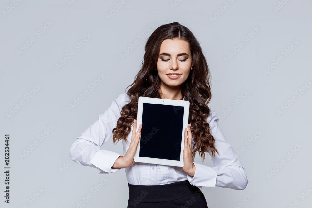 Portrait of young modern happy business woman in classic suit. Attractive female in smart casual wear holding a tablet. Place for your text or image. Portrait of young modern happy business woman in classic suit. Attractive female in smart casual wear holding a tablet. Place for your text or image.