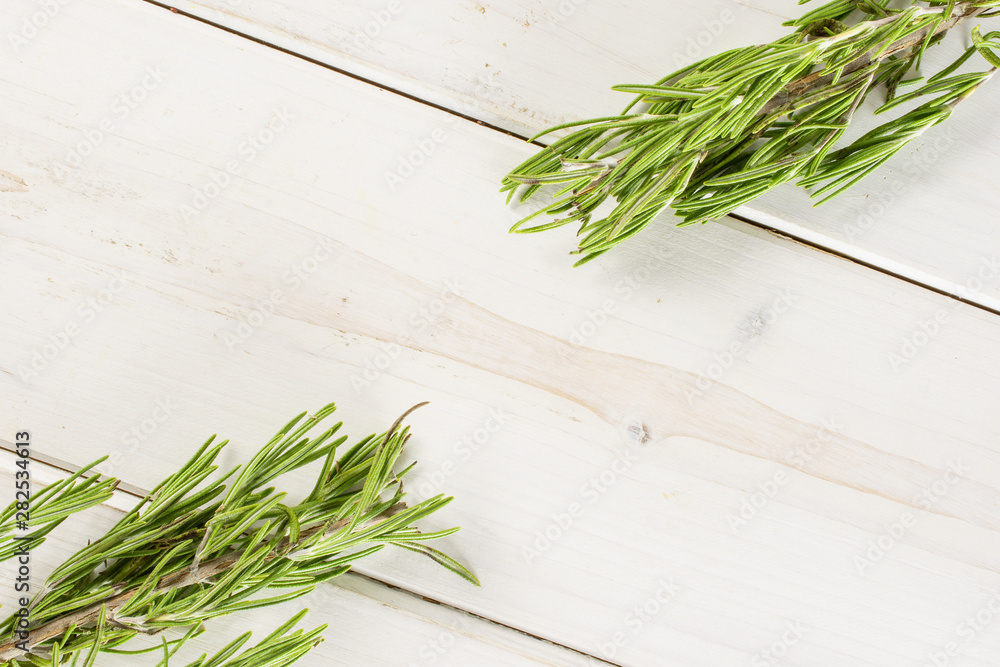Group of two whole fresh evergreen sprig of rosemary flatlay on white wood Group of two whole fresh evergreen sprig of rosemary flatlay on white wood