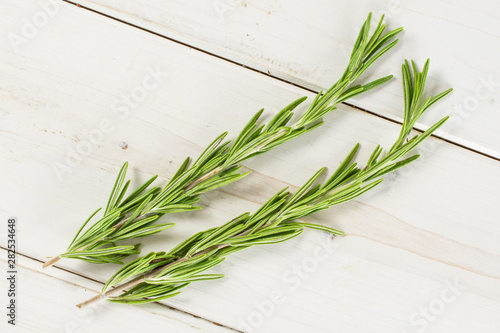 Group of two whole fresh evergreen sprig of rosemary flatlay on white wood