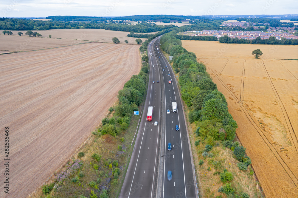 Aerial View over Motorway Across Ripe Grain Fields in UK