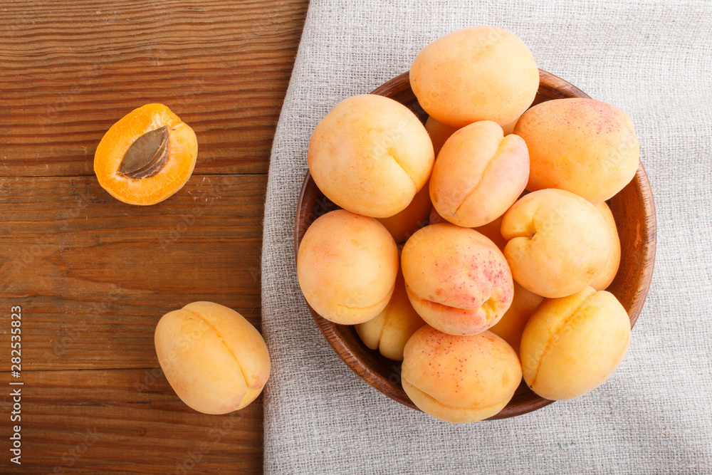 Fresh orange apricots in wooden bowl on wooden background. top view.