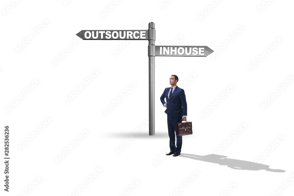 Businessman at crossroads deciding between outsourcing and inhou Businessman at crossroads deciding between outsourcing and inhou