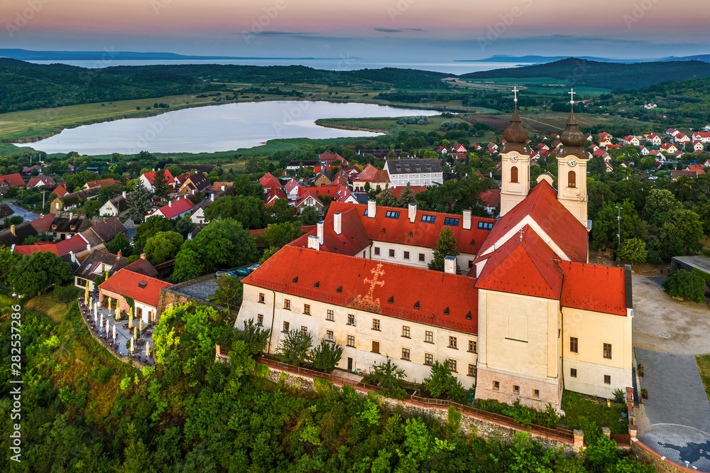 Tihany, Hungary - Aerial drone view of the famous Benedictine Monastery of Tihany (Tihany Abbey) with Inner lake and beautiful golden sunrise over Lake Balaton