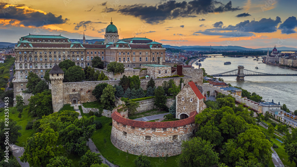 Budapest, Hungary - Aerial view of the famous Buda Castle Royal Palace with Szechenyi Chain Bridge and Hungarian Parliament building at sunset time with colorful sky