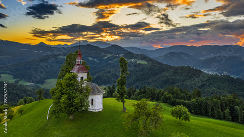 Skofja Loka, Slovenia - Amazing colorful sunset at the beautiful Sveti Tomaz (Saint Thomas) hilltop church with Julian Alps at the background at summer time