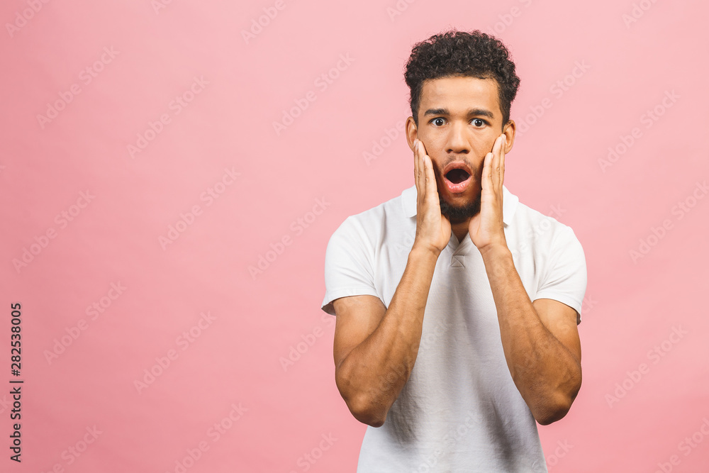 Portrait of young amazed man with afro hairstyle in white t-shir, looking in camera with opened mouth and shocked expression. Portrait of young amazed man with afro hairstyle in white t-shir, looking in camera with opened mouth and shocked expression.