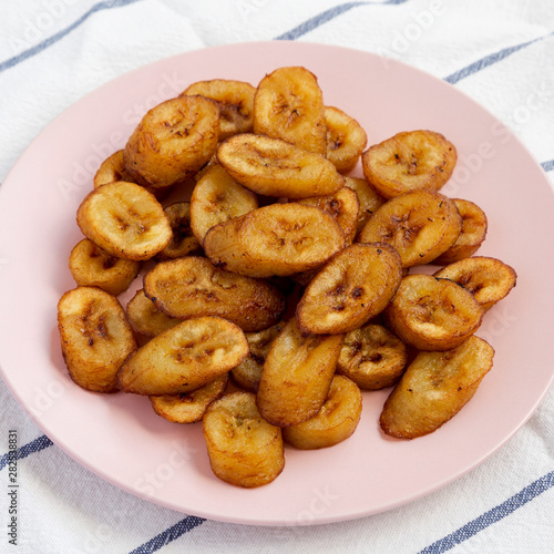 Homemade fried plantains on a pink plate, side view. Close-up. © Liudmyla