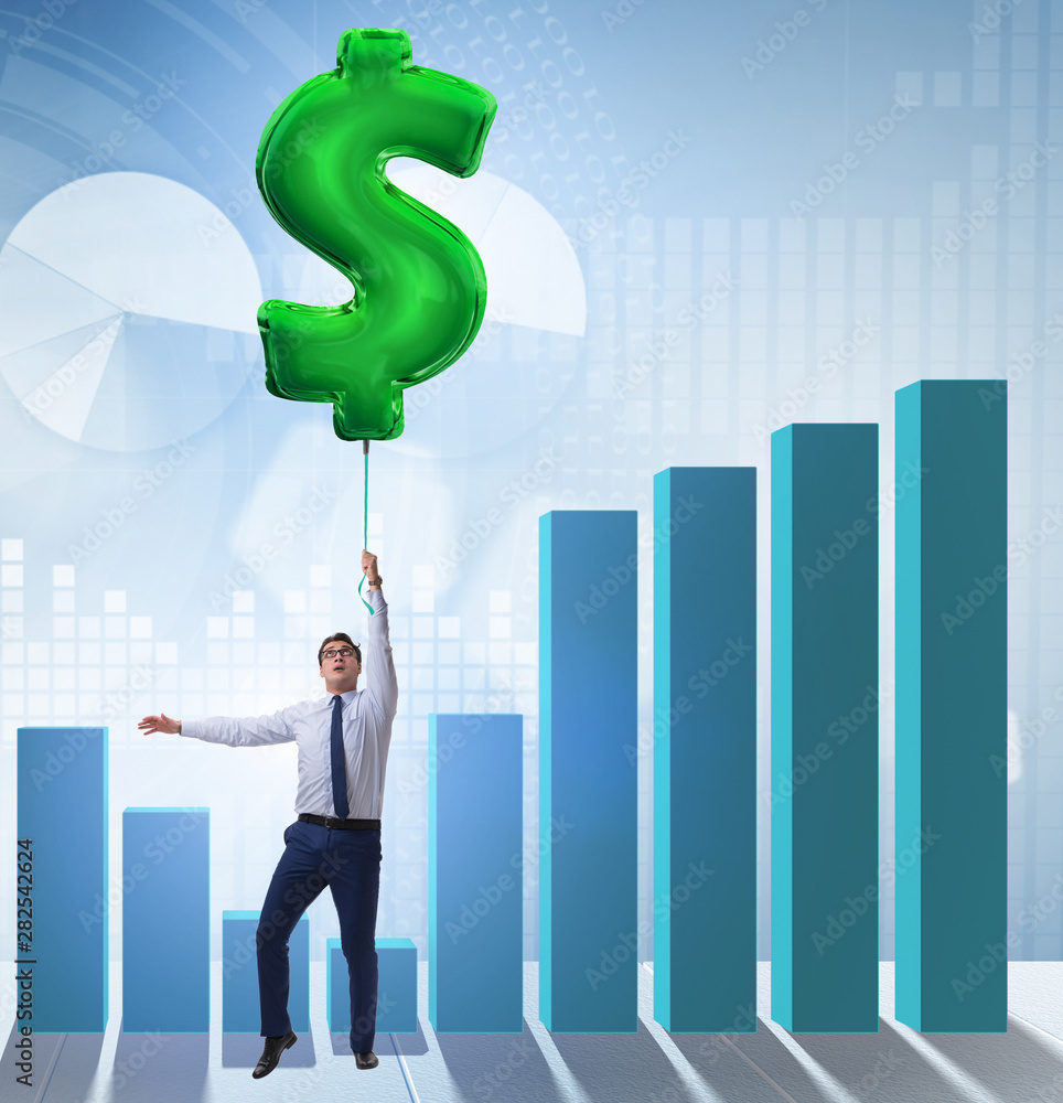 Businessman flying on dollar sign inflatable balloon over financ Businessman flying on dollar sign inflatable balloon over financ