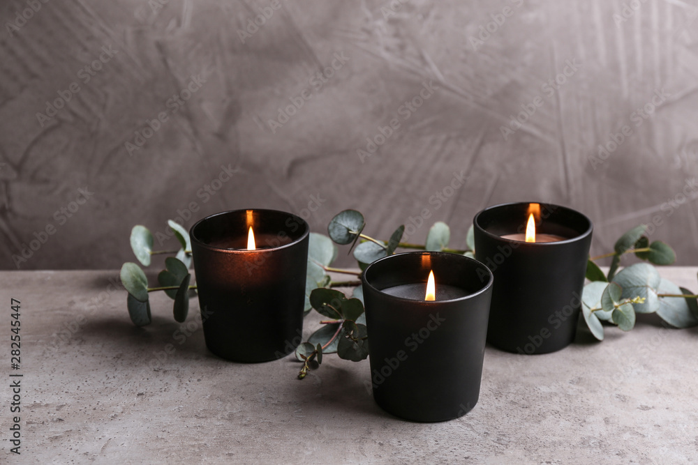 Burning candles and green branches on table - obrazy, fototapety, plakaty 