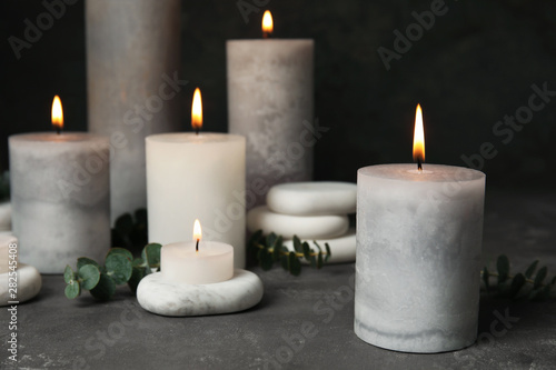 Composition with burning candles  spa stones and eucalyptus on grey table