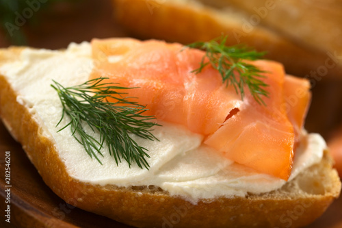 Canape of smoked salmon and cream cheese on wholewheat bun garnished with dill (Selective Focus, Focus on the front of the dill on the left)