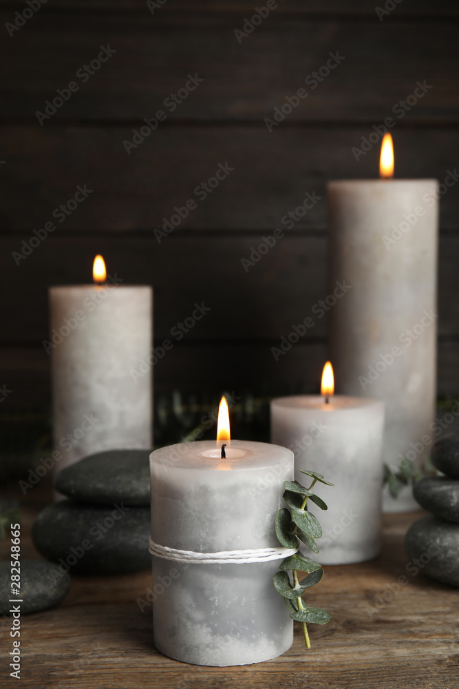 Composition with burning candles, spa stones and eucalyptus on wooden table, space for text Composition with burning candles, spa stones and eucalyptus on wooden table, space for text