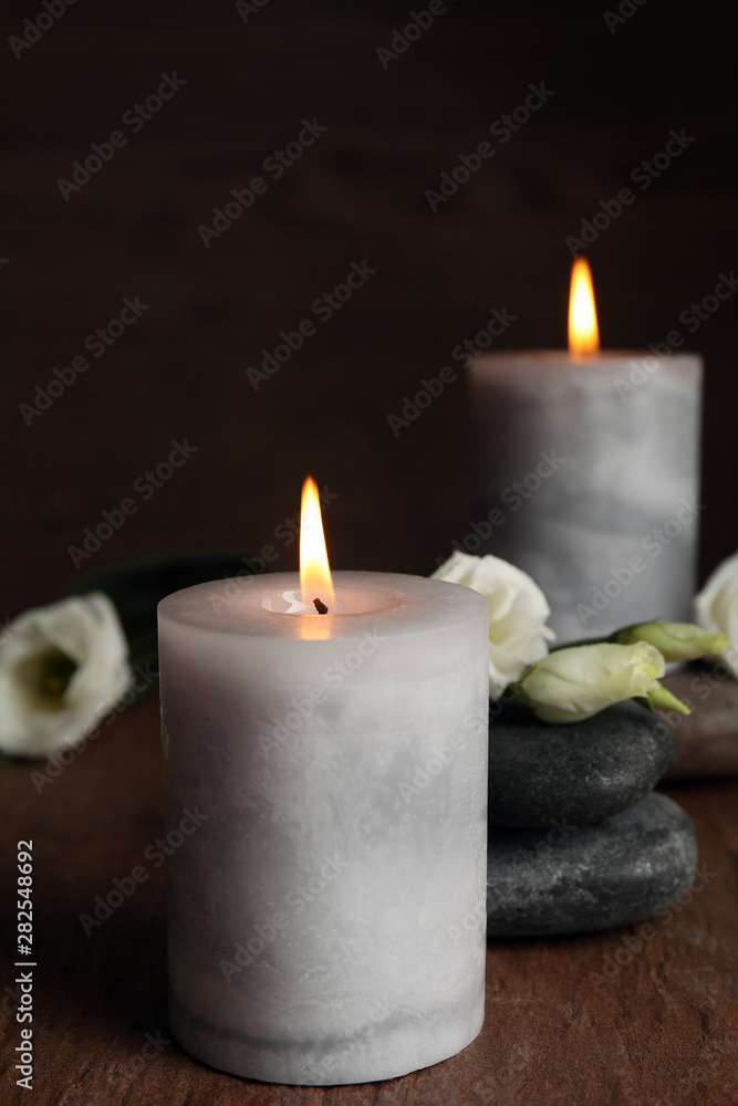 Burning candles, spa stones and flowers on wooden table, space for text