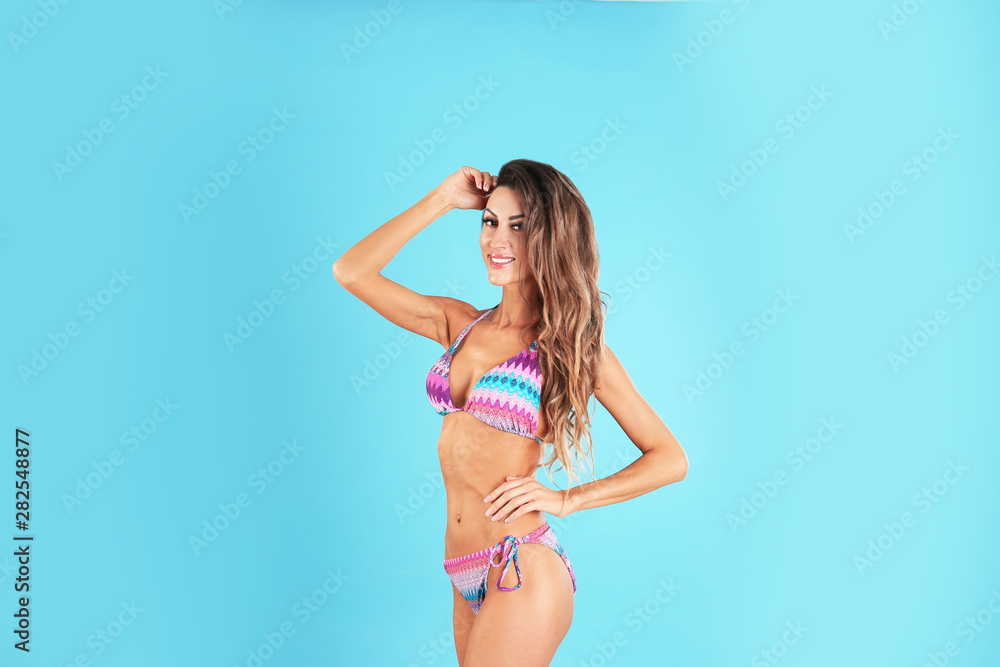 Fototapeta premium Pretty sexy woman with beautiful slim body in stylish bikini on color background