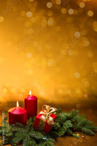 Gifts with bows  burning red candles and spruce branch on a golden background.