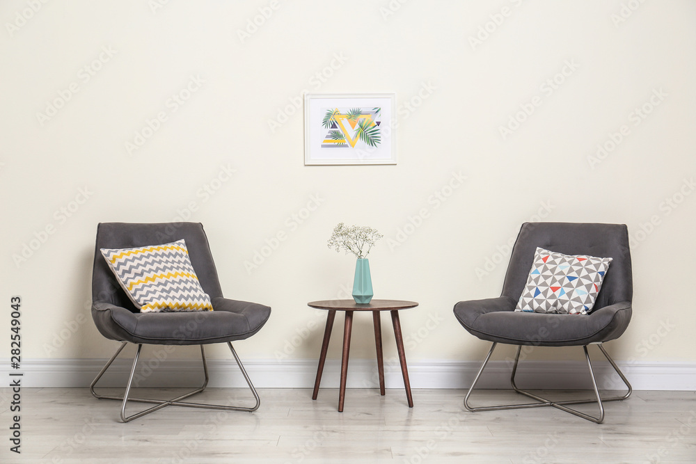 Fototapeta premium Room interior with modern chairs and table near light wall