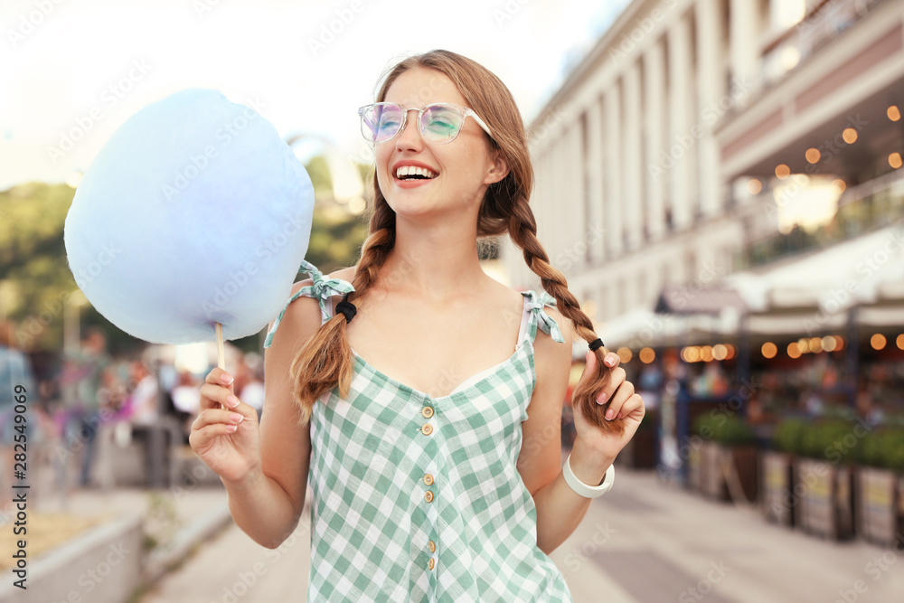 Naklejka premium Young woman with cotton candy on city street