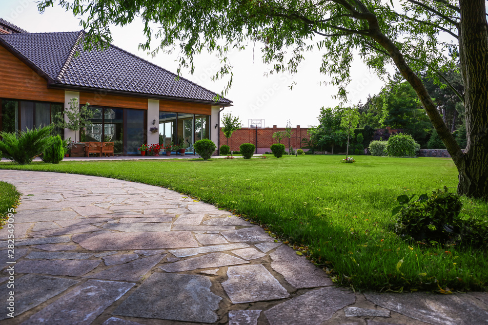Beautiful landscape with green garden near modern house on sunny day Beautiful landscape with green garden near modern house on sunny day