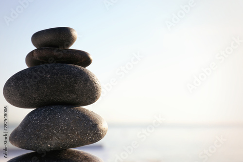 Stack of dark stones against blurred background  space for text. Zen concept