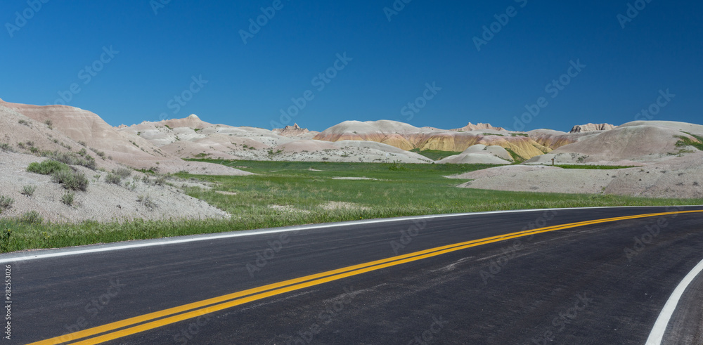 Highway running through arid yellow mound landscape