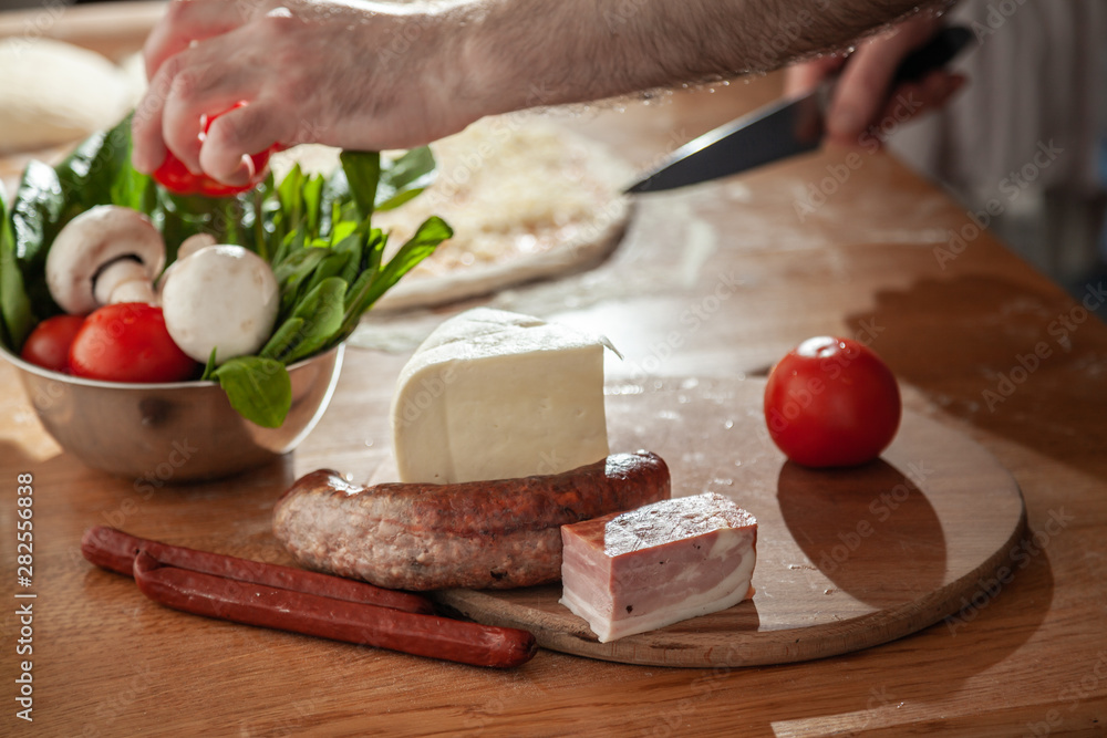 A man is preparing pizza. Close-up slices ingredients. A man is preparing pizza. Close-up slices ingredients.