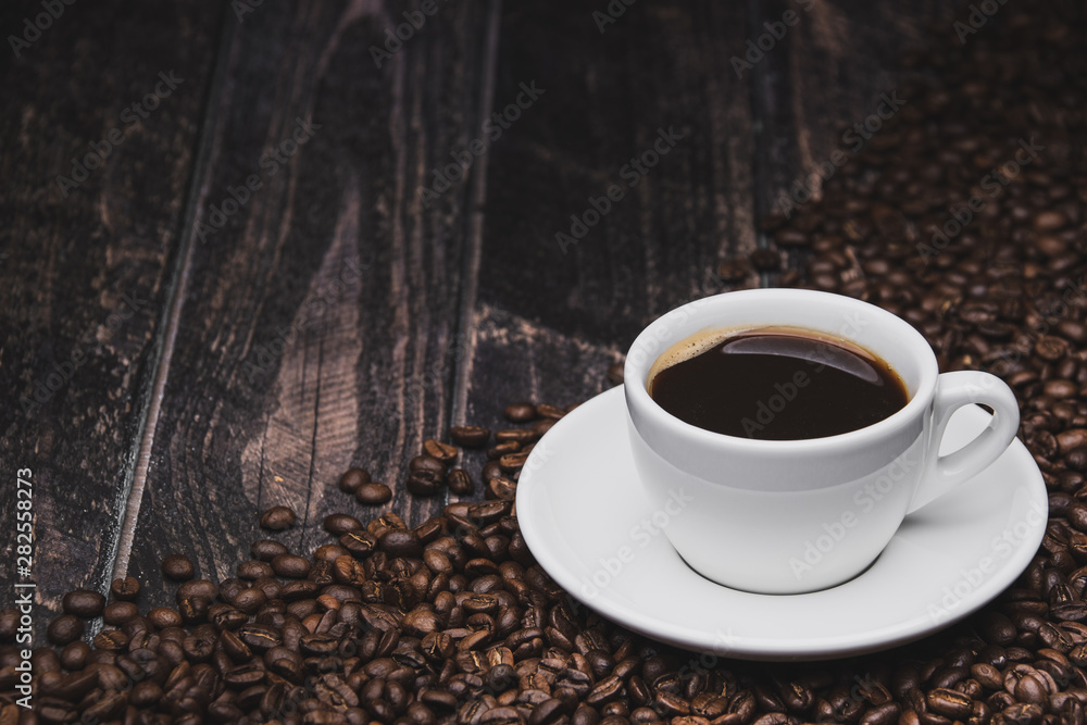Fototapeta premium cup of coffee on with beans brown wooden background