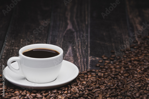 cup of coffee with beans on brown wooden background