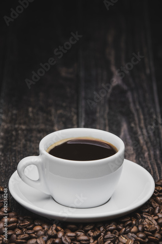 close up cup of coffee with beans on brown wooden background