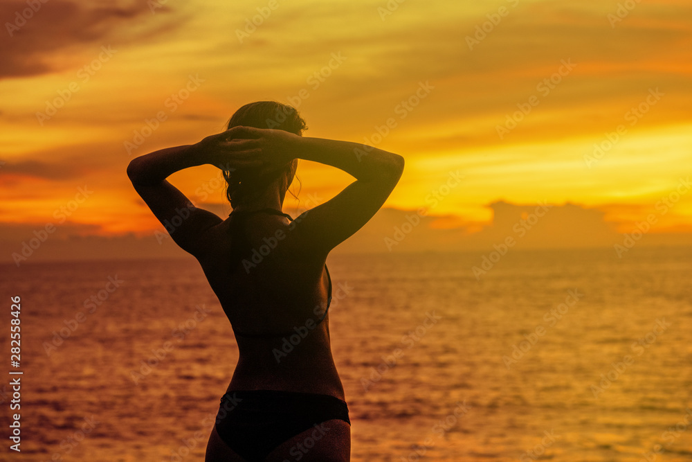 Fototapeta premium The GIRL admires the beautiful sunset, hands behind his head