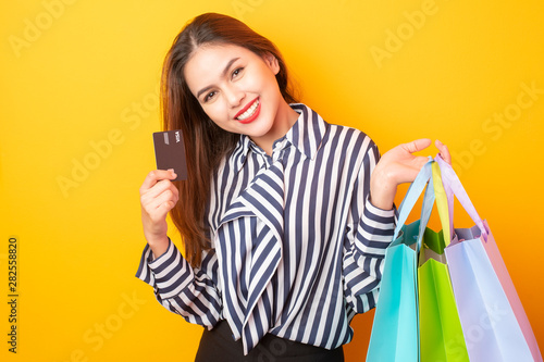 Happy shopping woman on yellow background