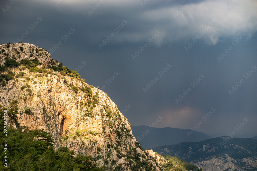 Cave on the mountain. Sunset lights and cloudy sky.