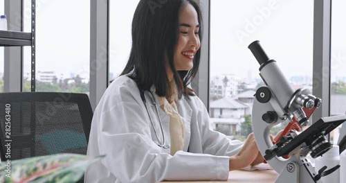 Panning scene video of Asian beautiful female doctor using tablet computer during doing her experiment in laboratory room.
