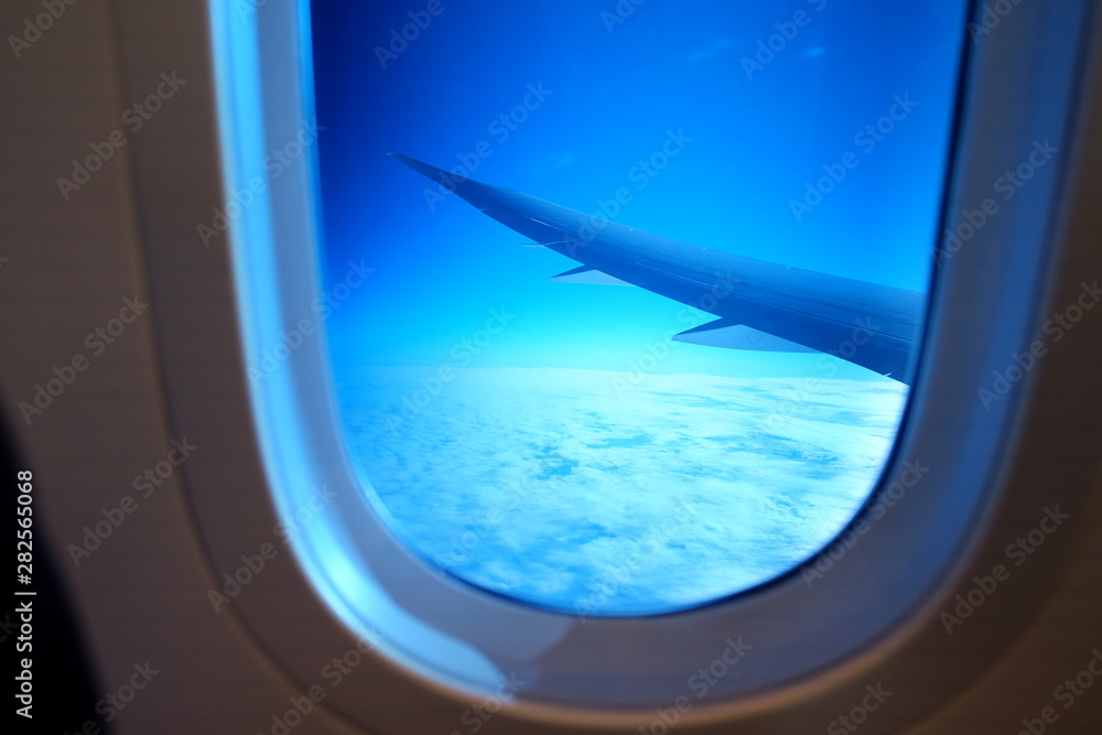 View from airplane window with sky and white clouds in a blue window View from airplane window with sky and white clouds in a blue window