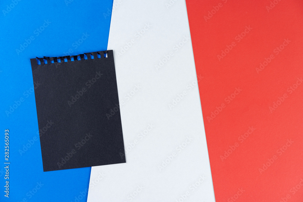 Plakat Blacklist France. Mourning, ban, sanctions, politics. black sheet from notebook lies on French flag. Mock up, copy space, pattern, cardboard texture.