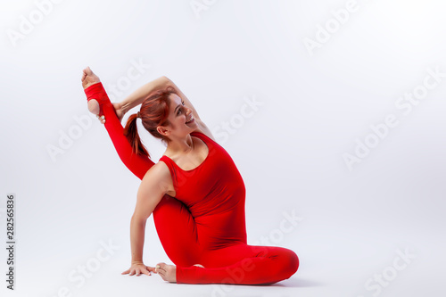 Beautiful slim woman in sports overalls  doing yoga, standing in an asana balancing pose - Heron Pose  on white  isolated background. The concept of sports and meditation. photo