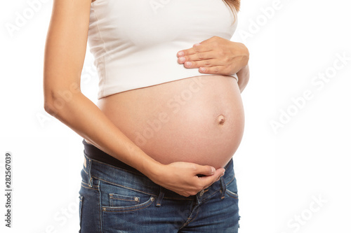 The pregnant woman gently touches her big belly. Waiting for a miracle. Close-up. Isolated over white background. © Анна Демидова