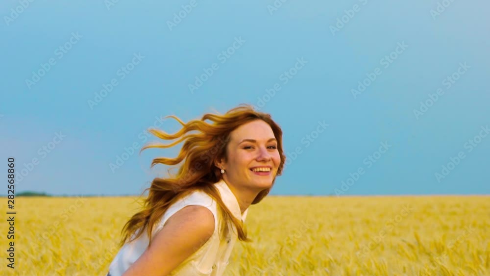 following shot of red haired woman running in wheat field in slow motion following shot of red haired woman running in wheat field in slow motion
