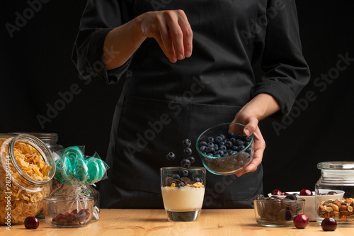 Yogurt falls asleep in sweet blackberries, frozen in motion. Cooking breakfast cereal, granules, breakfast cereals, cereals, berries of a cherry, and blueberries. Horizontal photo