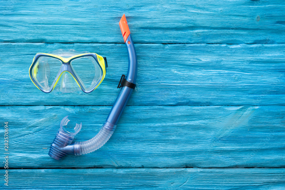 Underwater mask and snorkel on a blue wooden table background with a copy space.