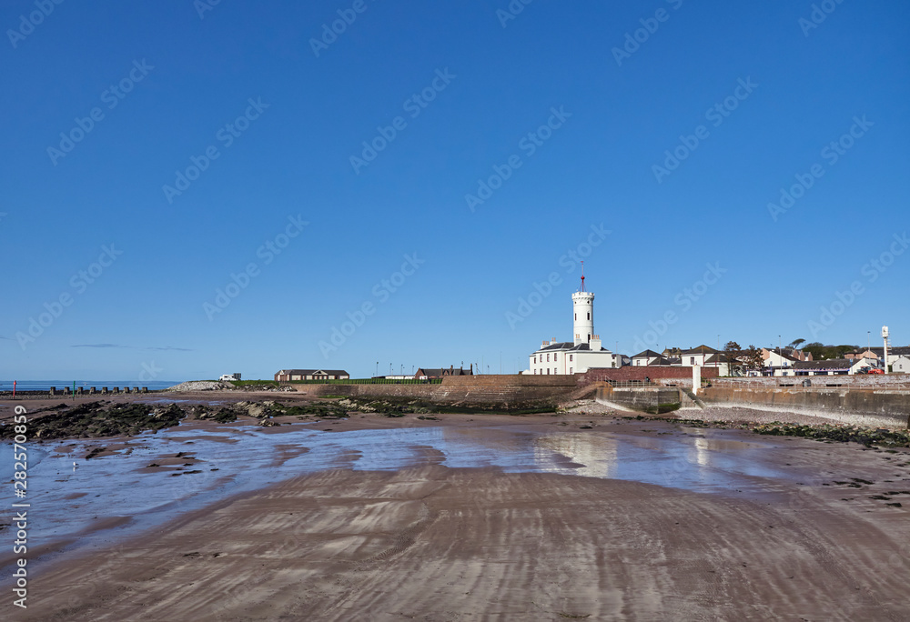 Fototapeta premium Looking over the small Beach adjacent to Arbroath Harbour south to the Signal Tower Museum one early Summers morning in May. Arbroath, Angus, Scotland.
