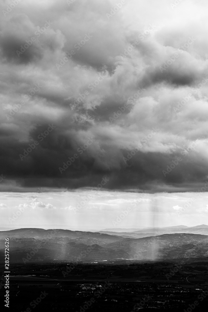 Obraz premium Sunray shines through clouds over the mountains in the middle of shadows