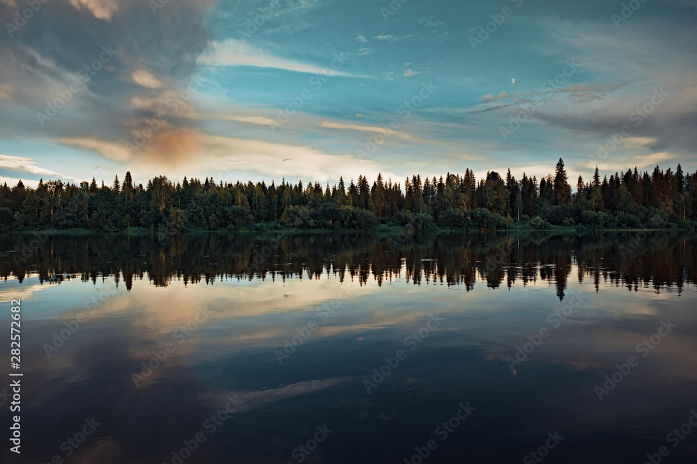 Forest river Bank at sunset with reflection in the water