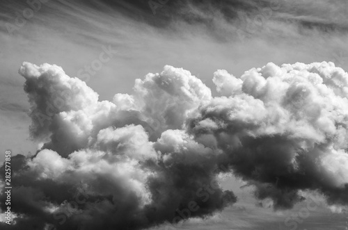 Large Cumulus cloud is depicted large against the background of Cirrus clouds black and white image, copy space, instagram.
