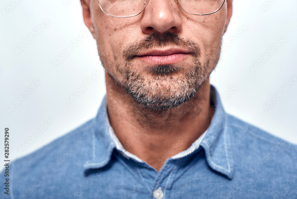 Fototapeta premium Perfect look. Cropped photo of bearded man in eyewear looking at camera while standing against grey background