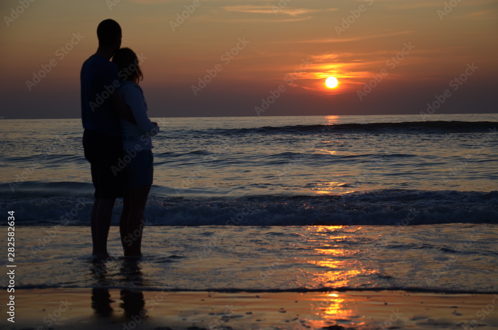 Couple amoureux devant un couché de soleil sur la plage