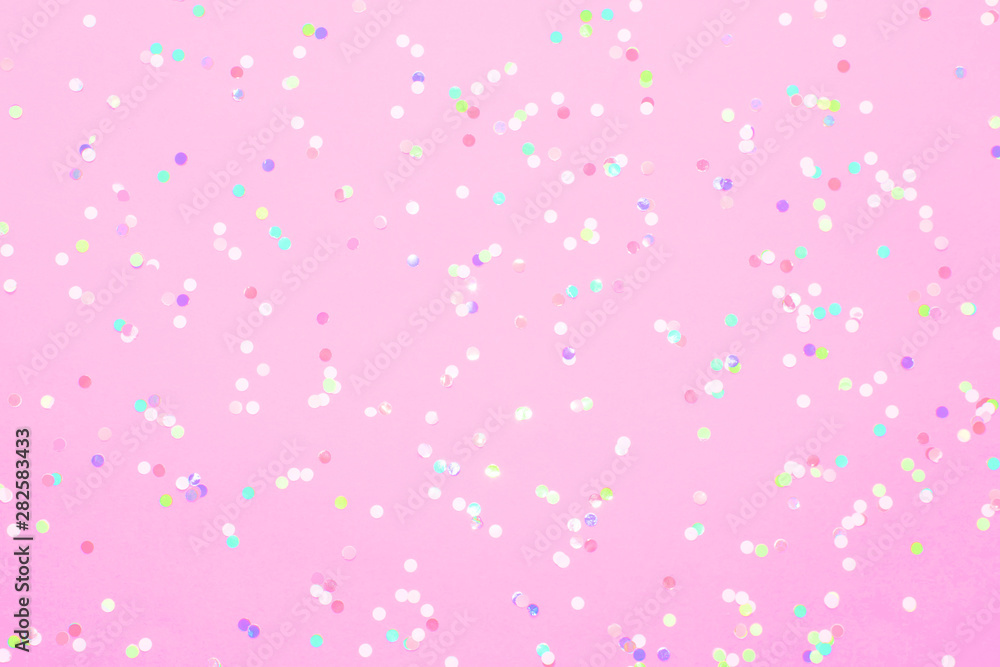 Colored confetti scattered on pink pastel paper Colored confetti scattered on pink pastel paper
