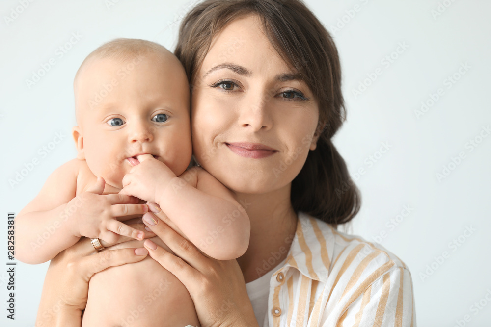 Happy mother with cute little baby on light background - obrazy, fototapety, plakaty 