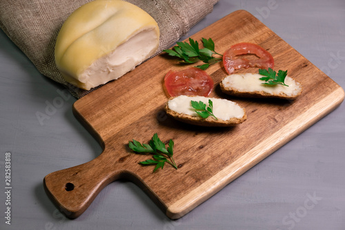 Arzua Ulloa cheese on a wood table with tomato and parsley